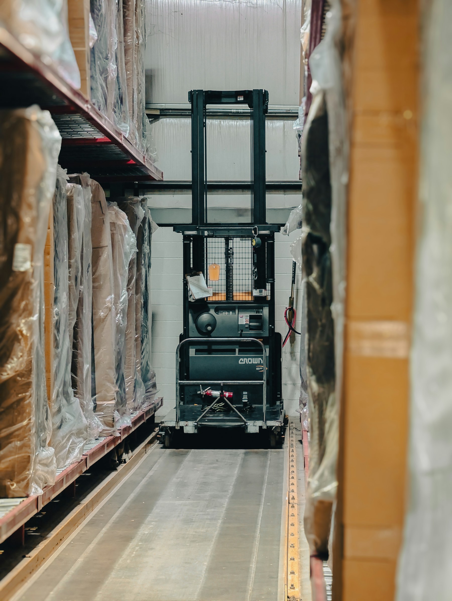 Forklift positioned between warehouse inventory racks